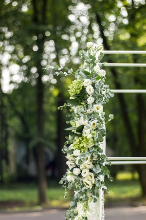 White wedding flowers over arch in outdoor park.の写真素材