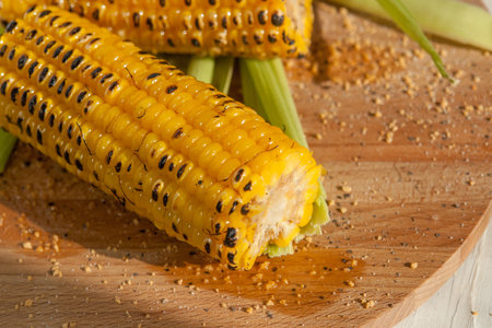 two grilled corn on a wooden plate.