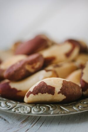 Brazil nuts in metal plate over the white wooden tableの写真素材