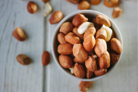 Dry peanuts in white bowl over the white table.