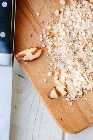 Brazil nuts on wooden board chopped by chief knife.の写真素材