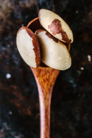 Brazil nuts in wooden spoon over the black metal backgroundの写真素材