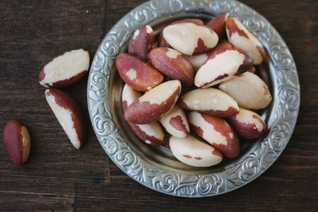 Brazil nuts in vintage arabic plate over the wooden tableの写真素材