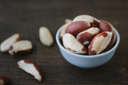 Brazil nuts on white ceramic bowl over the wooden table.の写真素材