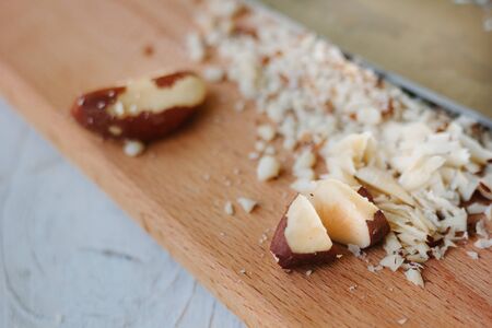 Brazil nuts on wooden board chopped by chief knife.の写真素材