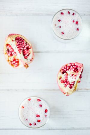 Traditional indian lassi - cold yougurt drink on white table with pomegranate seeds.の写真素材