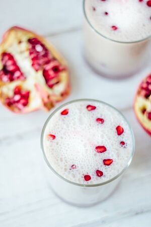 Traditional indian lassi - cold yougurt drink on white table with pomegranate seeds.の写真素材