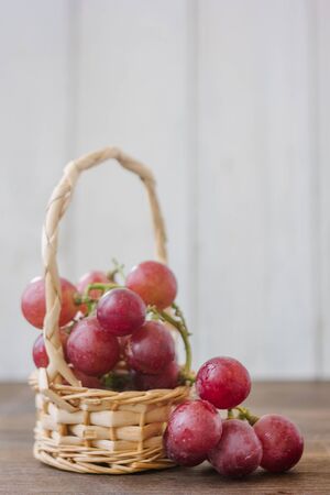 Basket filled with red grapes over the wooden tableの写真素材