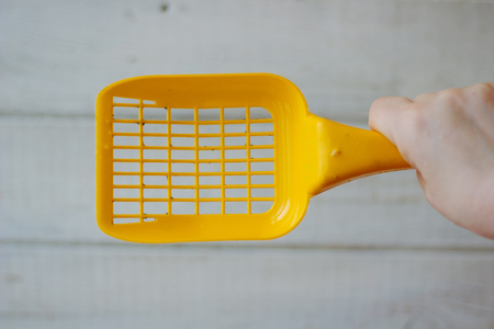 Yellow plastic scoop for cleaning pet litter over the wooden background.の写真素材