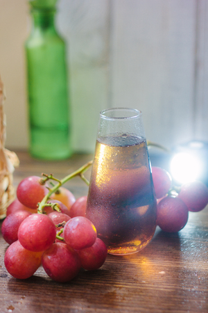 Fresh grape wine in glass over the wooden background.の写真素材