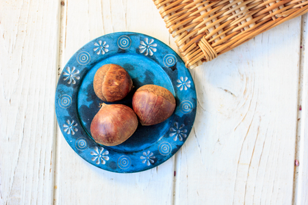 Chestnuts on blue ceramic plate over white table.の写真素材