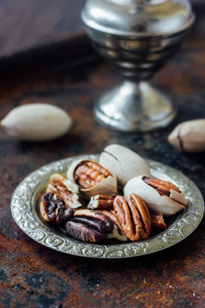 Pecan nuts on metal plate over black rustic surface