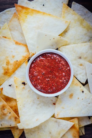 Hot salsa dip over the hip of nachos chips - organic home made sauceの写真素材