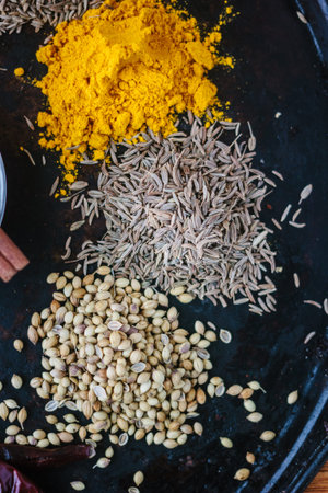 Coriander, cumin and turmeric spices over black metal plate