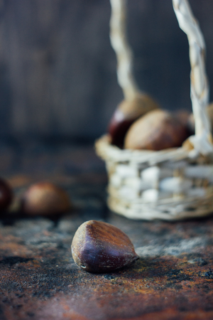 Fresh chestnuts in basket over black rustic surfaceの写真素材