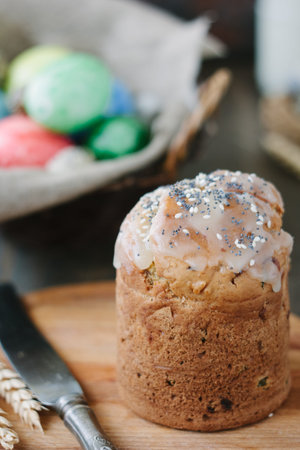 Easter cake standing on board against the basket with easter eggs
