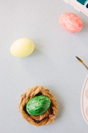 Green color easter egg in small nest over bright background.
