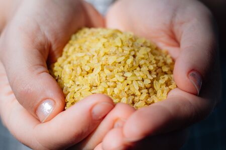 Woman holding natural organic bulgur cereal in hands.の写真素材