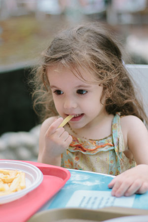 Little kid girl having fun in a cafe or restaurant.