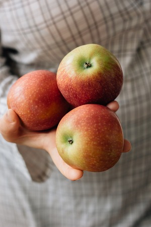 Three fresh apples in a woman hands.の写真素材