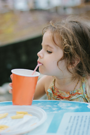 Little kid drinks cola at the cafe or restaurantの写真素材