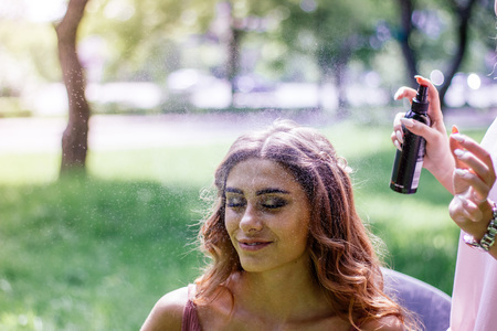 Stylist spraying hairs of young girl with hair spray.の写真素材
