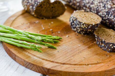 Fresh asparagus with hot bread on wooden kitchen board.の写真素材