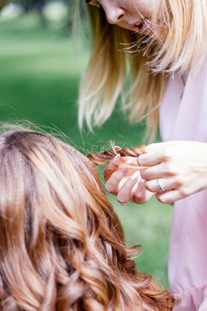 Braiding pigtales to young woman at outdoor session.の写真素材