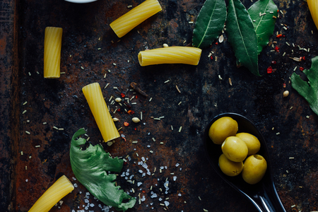 Tortiglioni pasta with ingredients on black metal surface.の写真素材