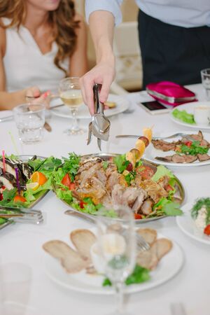 Hands with tongs lets pieces of christmas turkey for eating.の写真素材
