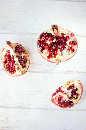 Parts of fresh pomegranate over white wooden surface.の写真素材