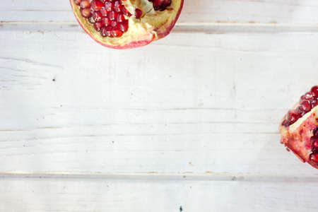 Parts of fresh pomegranate over white wooden surface.の写真素材