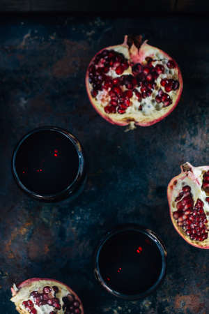 Fresh pomegranate wine in glass on black rustic surface.の写真素材