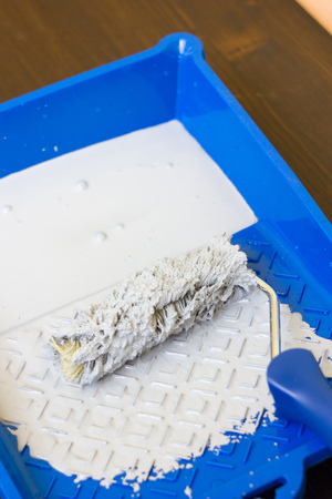 Blue paint tray with paint roller and paint inside it.の写真素材