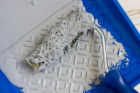 Blue paint tray with paint roller and paint inside it.の写真素材