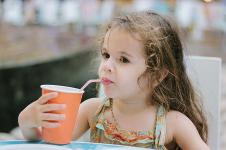Little kid drinks cola at the cafe or restaurant