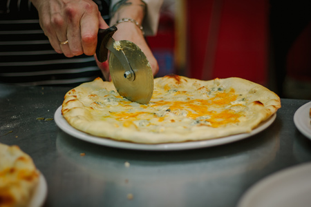 Chef cutting pizza with the round pizza cutter or knife.の写真素材