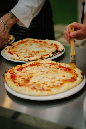 Chef smears olive oil to the top of pizza.の写真素材