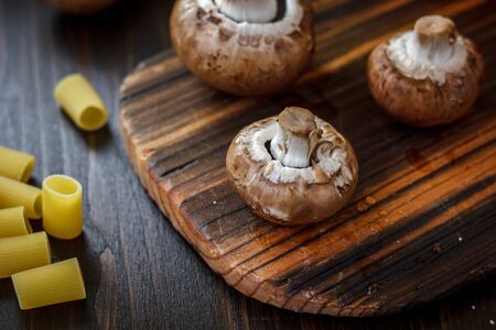 Mushrooms on board with fresh vegetables on background.の写真素材