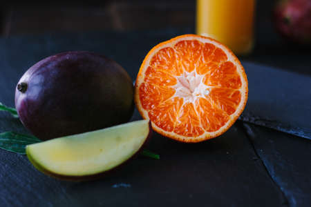 Mango and orange fruits over black slate board.の写真素材