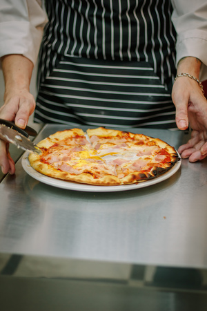Chef cutting pizza with the round pizza cutter or knife.の写真素材