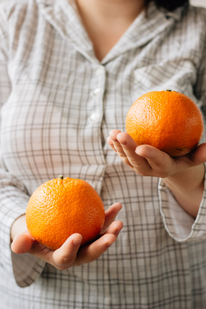 Woman holding two ripe oranges in her hands.の写真素材