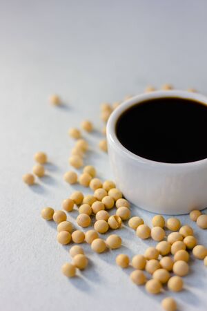 Soybean sauce surrounded by soy beans over white background.の写真素材