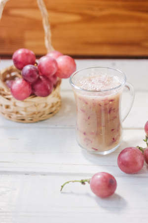 Grape smoothie over the white table whith grapesの写真素材