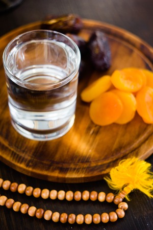 ramadan water for iftar on wooden board with rosary and dried fruits.の写真素材