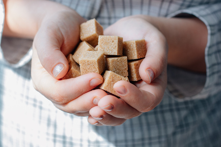 woman holds brown sugar cubes in handsの写真素材