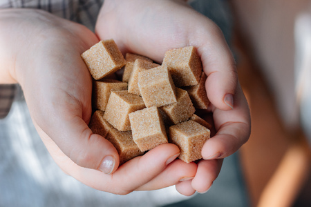 woman holds brown sugar cubes in handsの写真素材