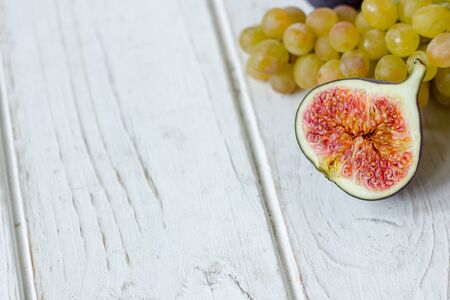 Fresh fruits - figs and grapes over white wooden backgroundの写真素材