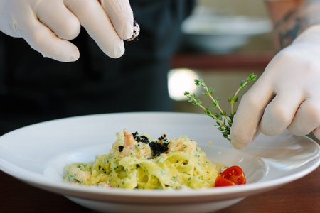 Chief dressing pasta with black truffle and herbs