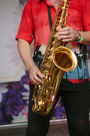 Saxophone player with the saxophone in arms, playing with it